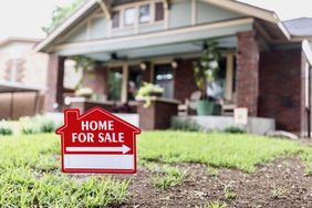 A house with a "Home For Sale" sign in the foreground
