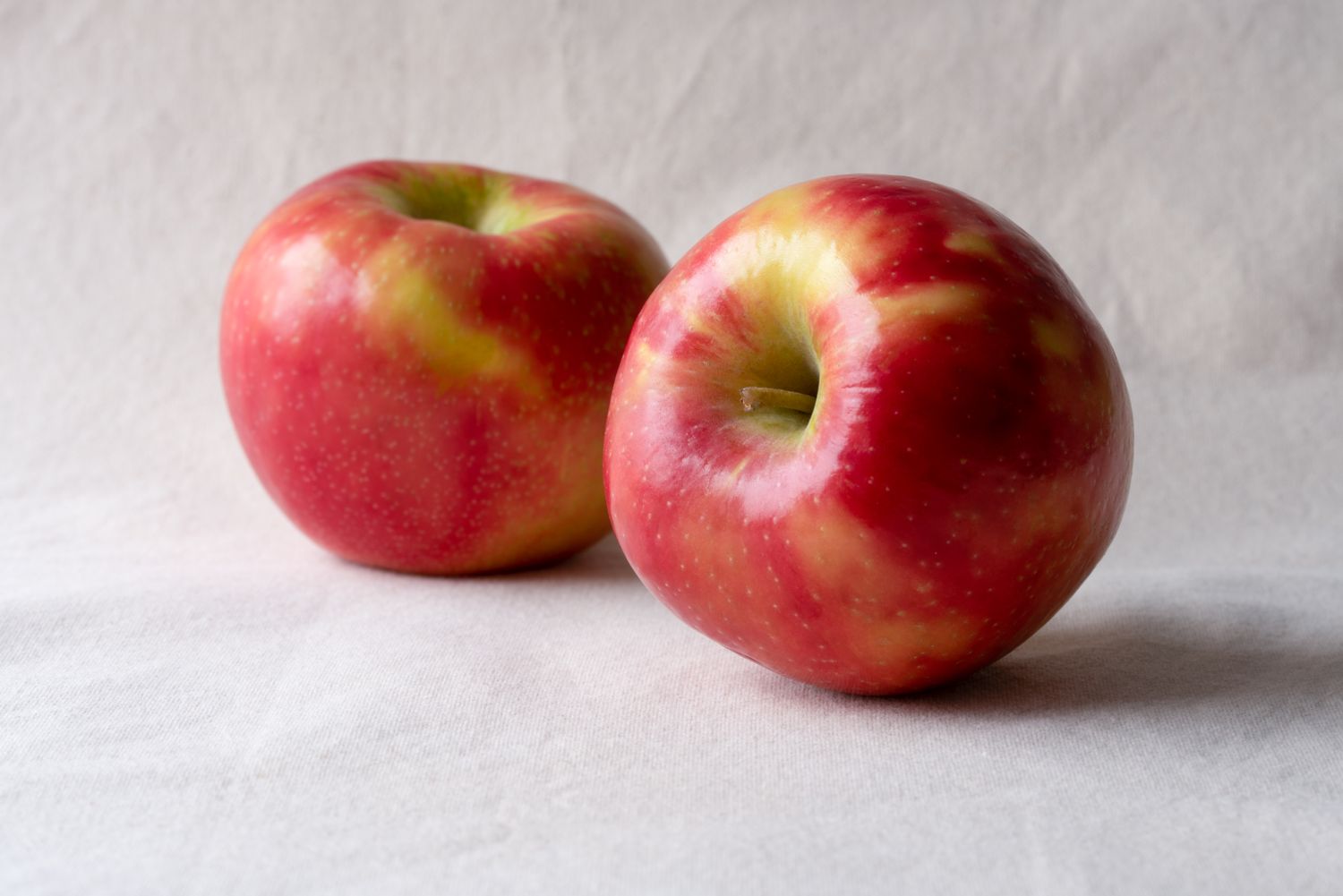 Two apples placed on a light surface side by side