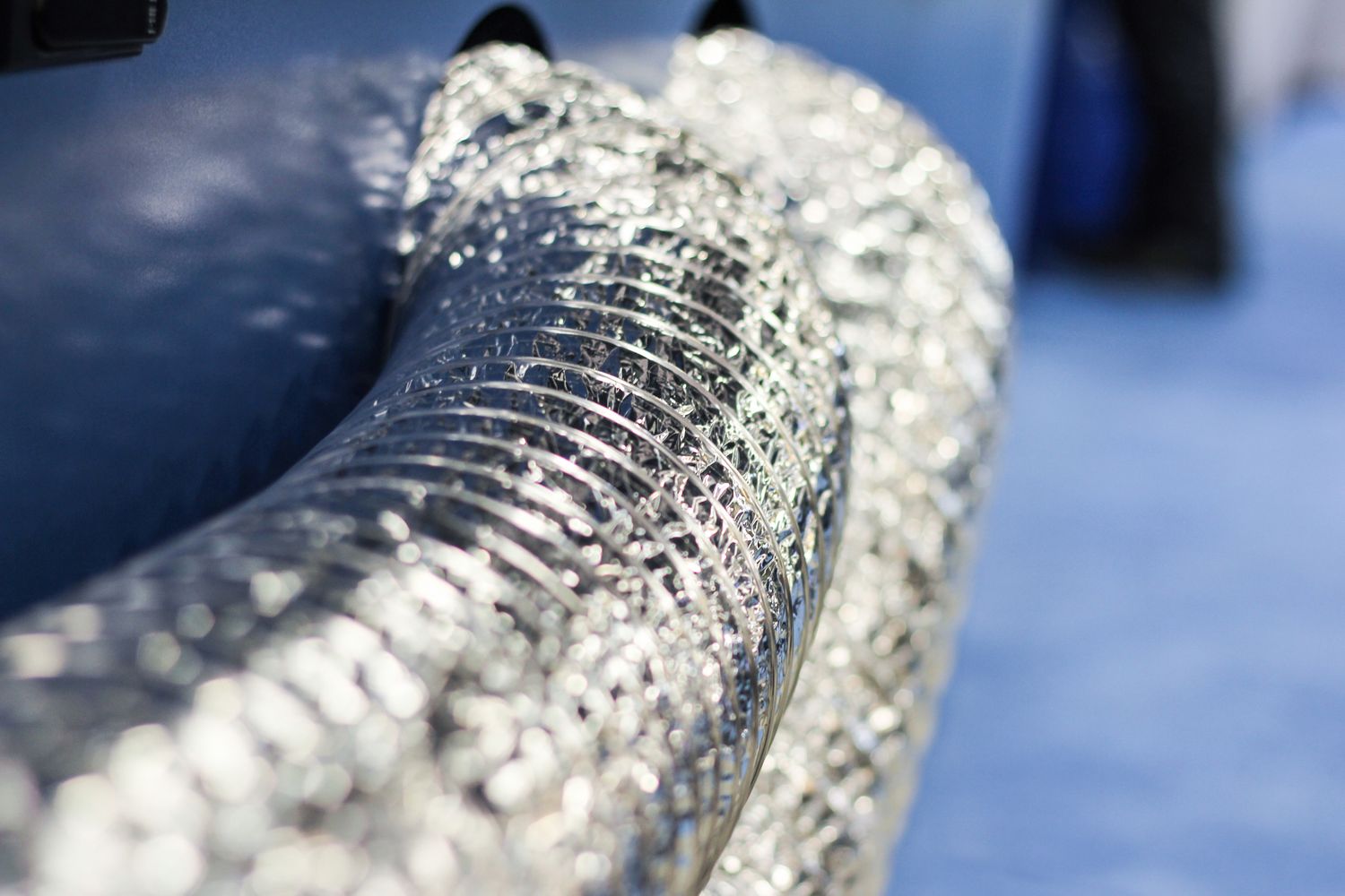 Closeup view of metallic flexible tubes connected to machinery industrial setting