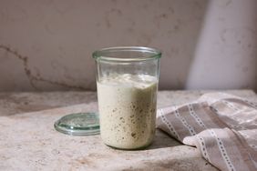 A jar of sourdough starter on a countertop with a cloth napkin beside it