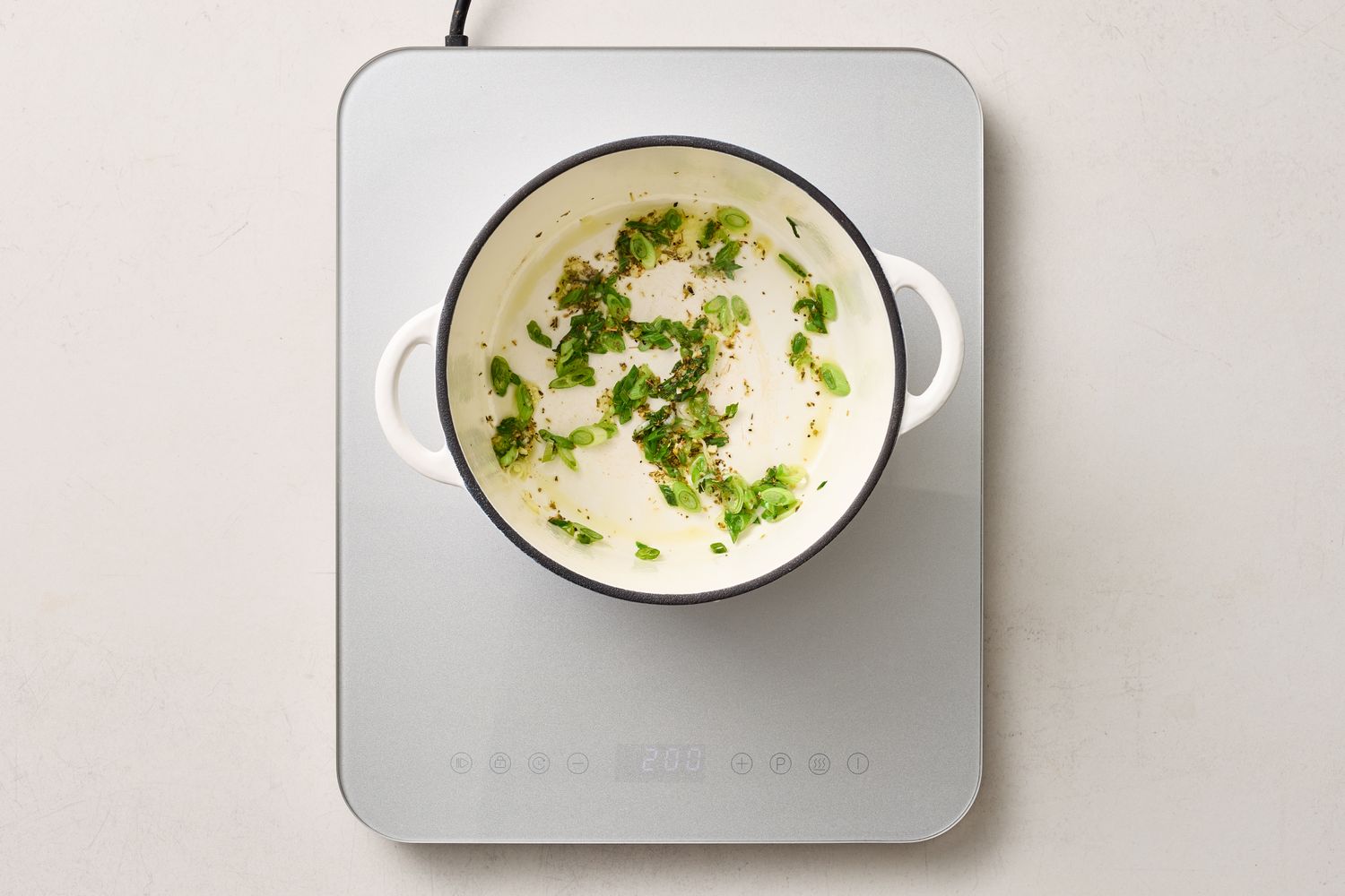 A pot on a hot plate with herbs and ingredients inside part of a cooking preparation
