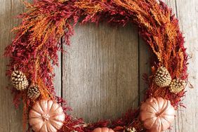 A fallthemed wreath with foliage pinecones and small pumpkin decorations