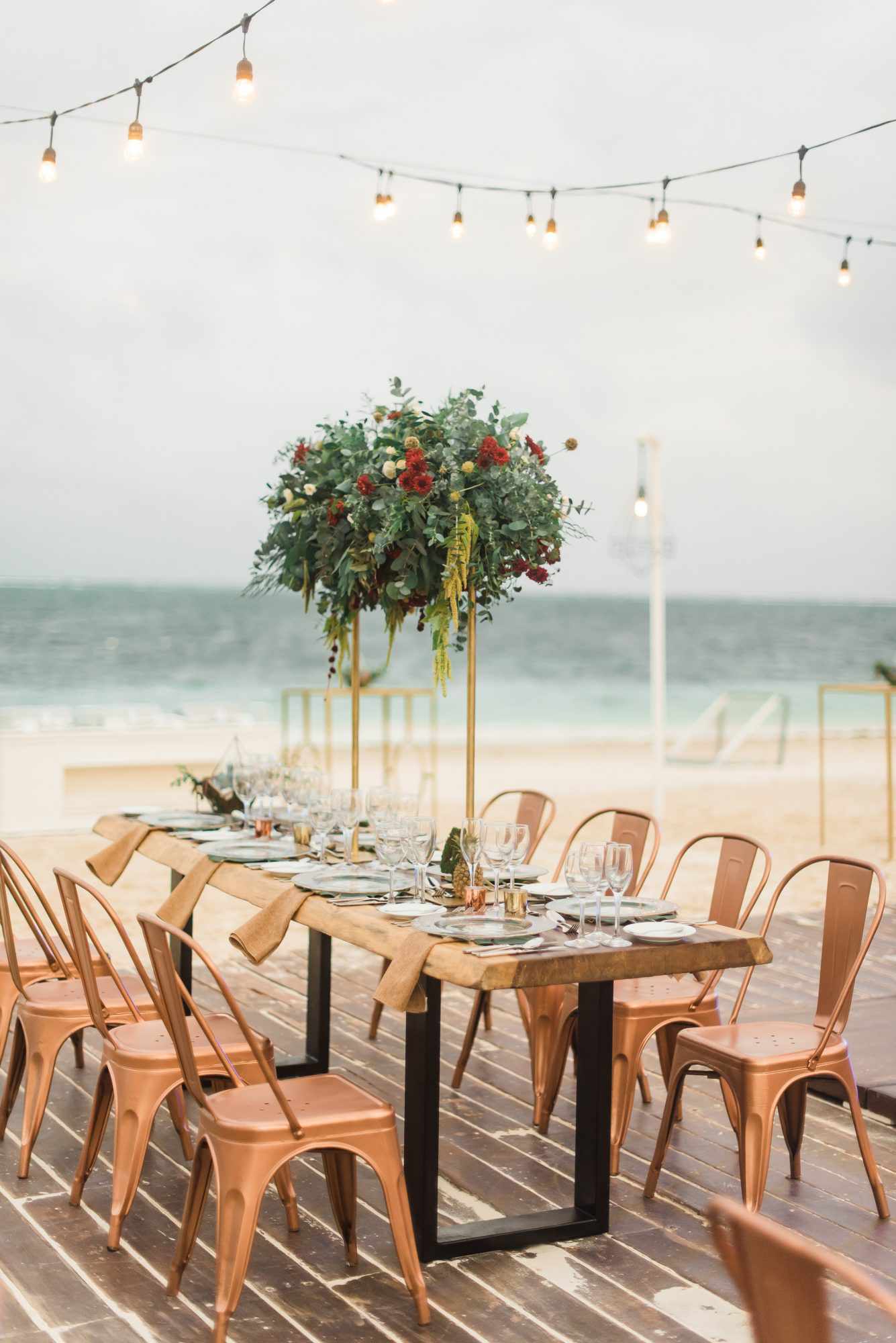 tall centerpiece with greenery and red flowers