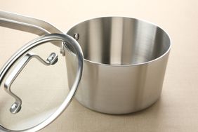 A stainless steel saucepan with a glass lid beside it