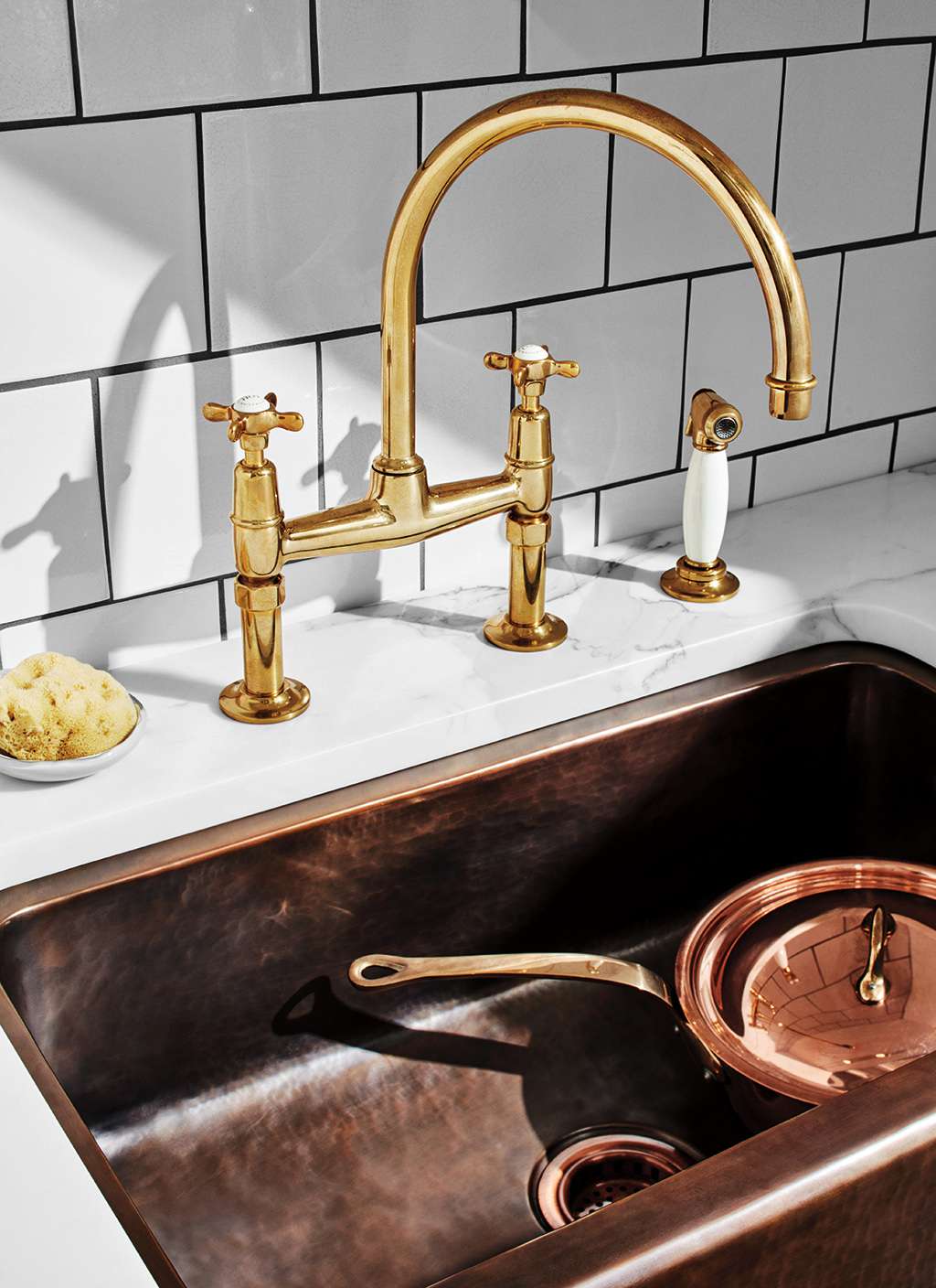 unlacquered brass faucet and sink with copper pot