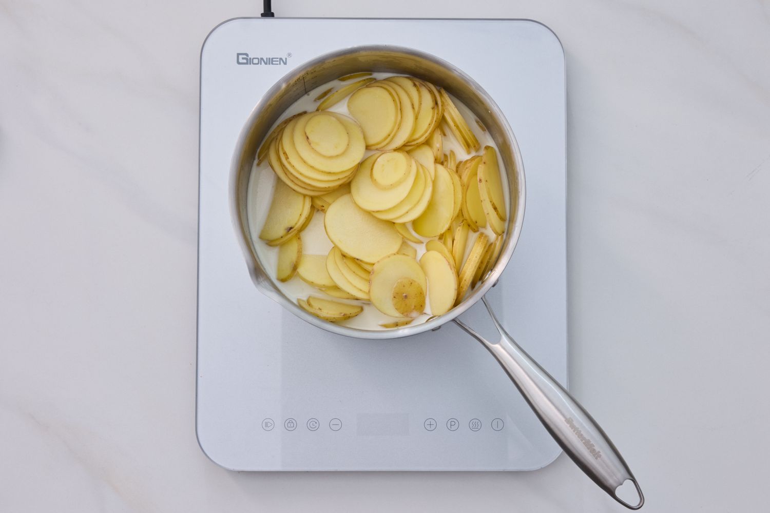 Sliced potatoes in a pot on an induction stove top
