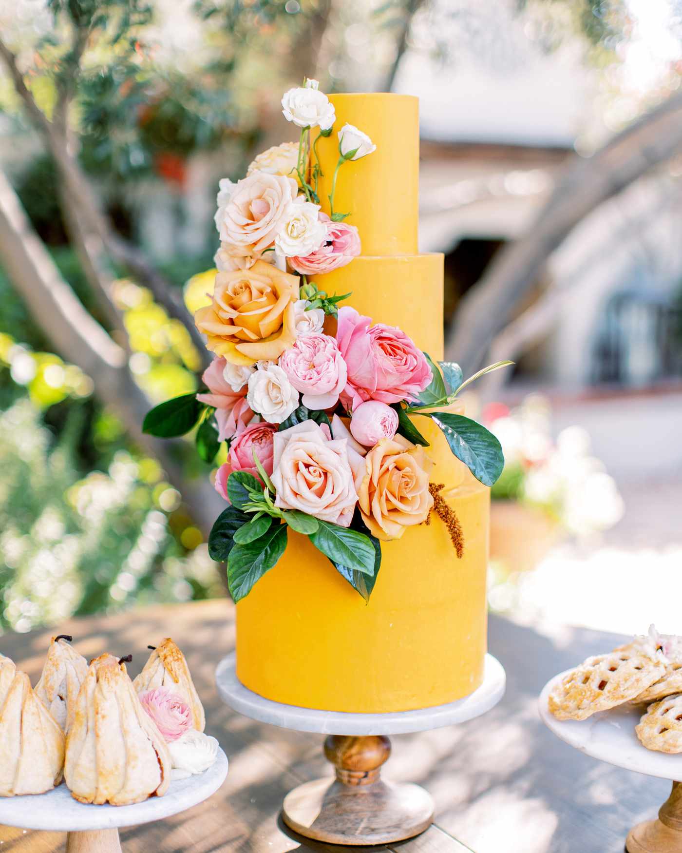 four tiered deep golden yellow frosted wedding cake with floral display