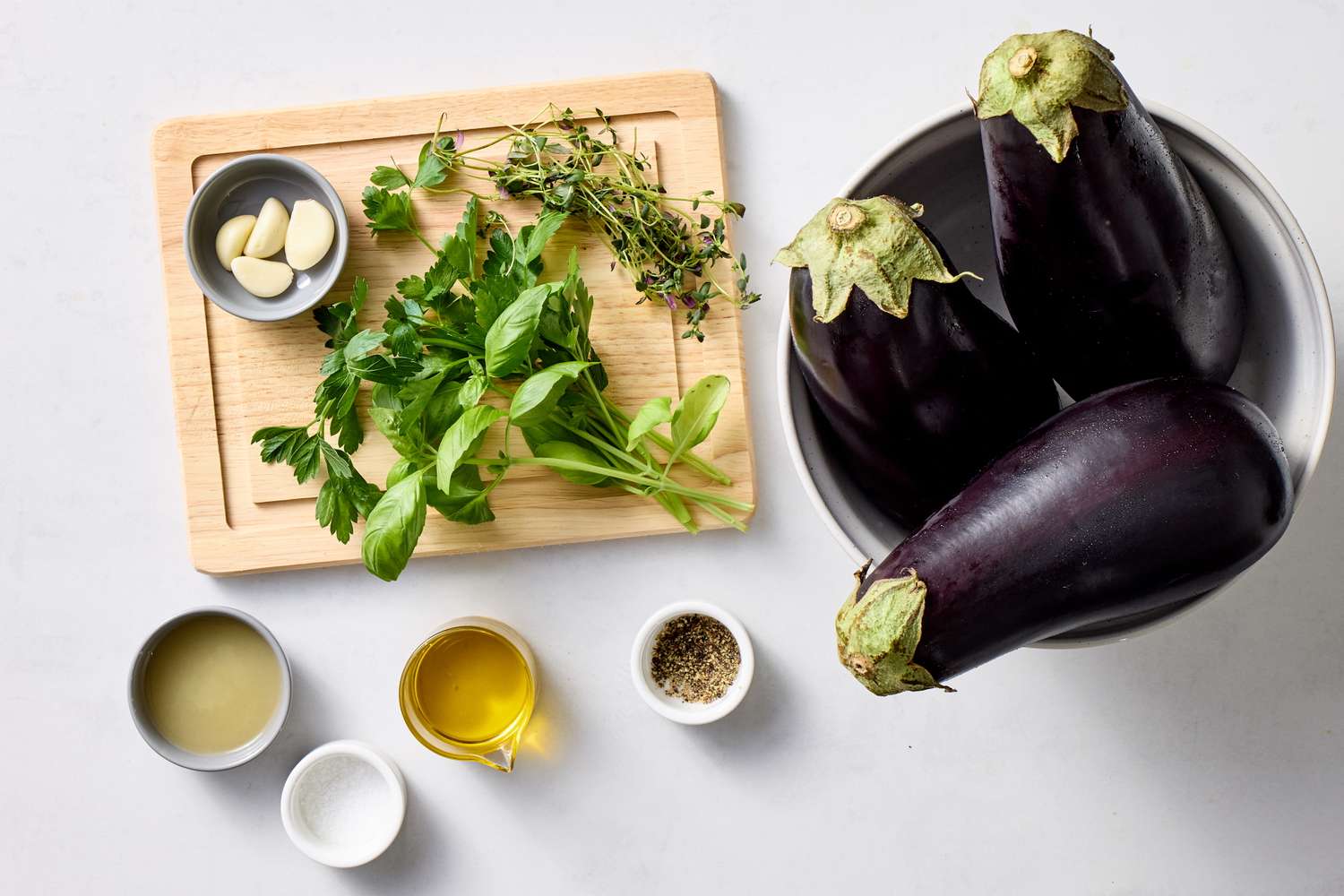 Eggplants herbs garlic oil lemon juice and seasonings on a table