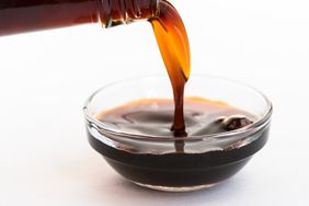 Pouring coconut aminos into glass bowl