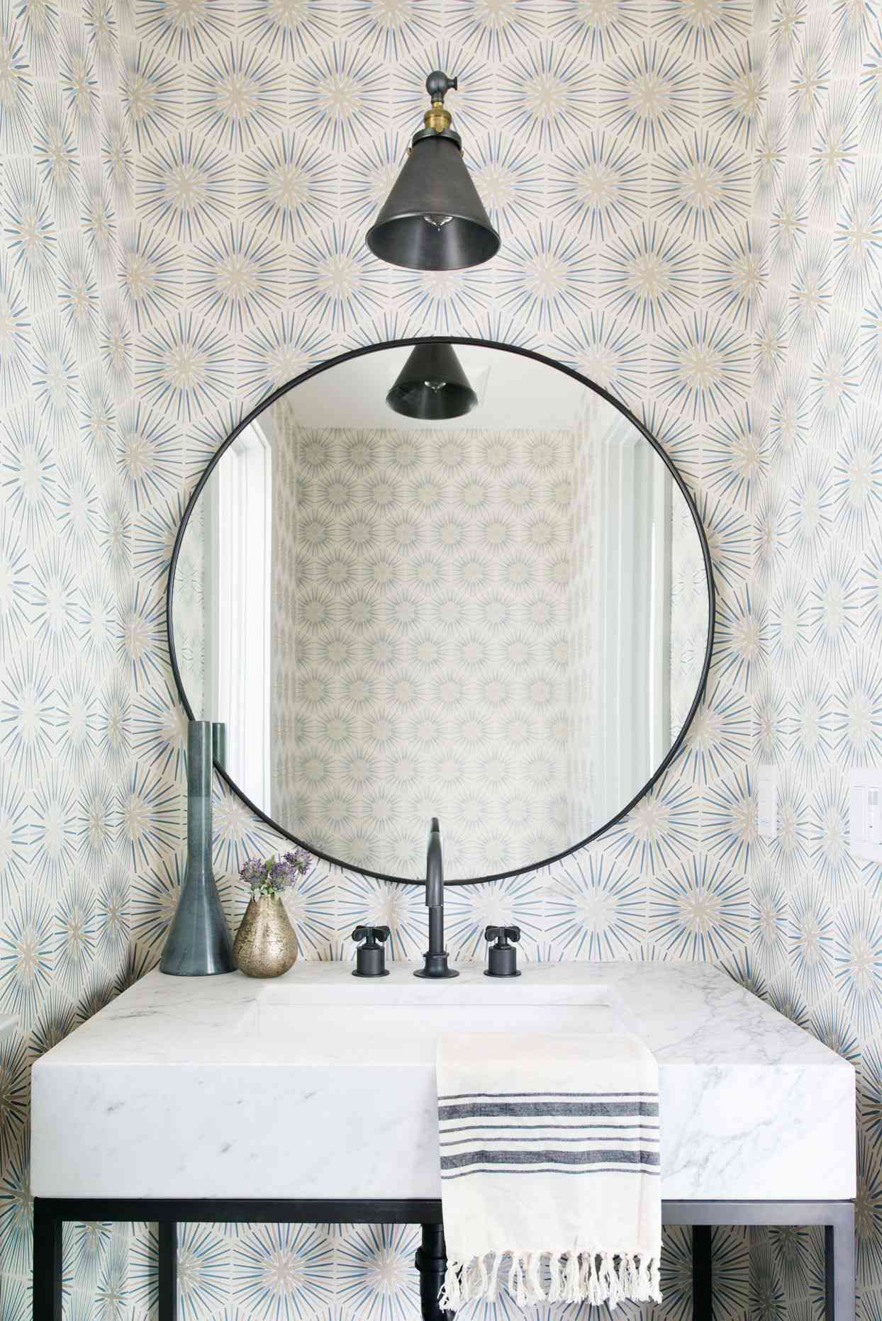 large circle mirror about white marble sink black metal frame