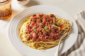 white plate of meat spaghetti sauce and pasta with fork