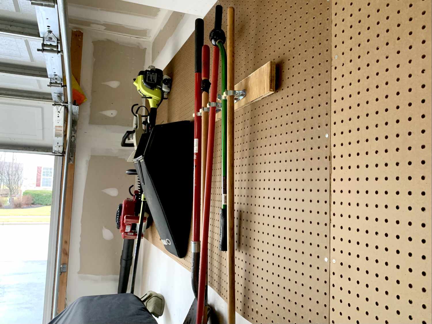 Pegboard wall in a garage with various tools and garden equipment organized on it