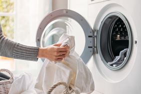 A person placing laundry into a washing machine