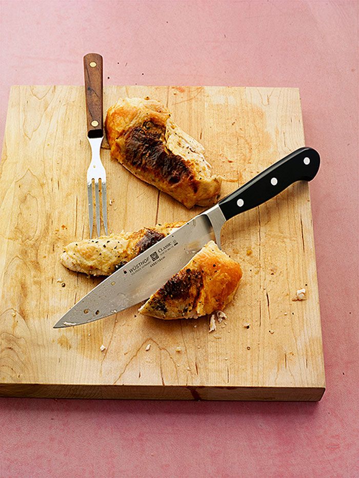 Carved chicken breast on a cutting board with a knife and fork