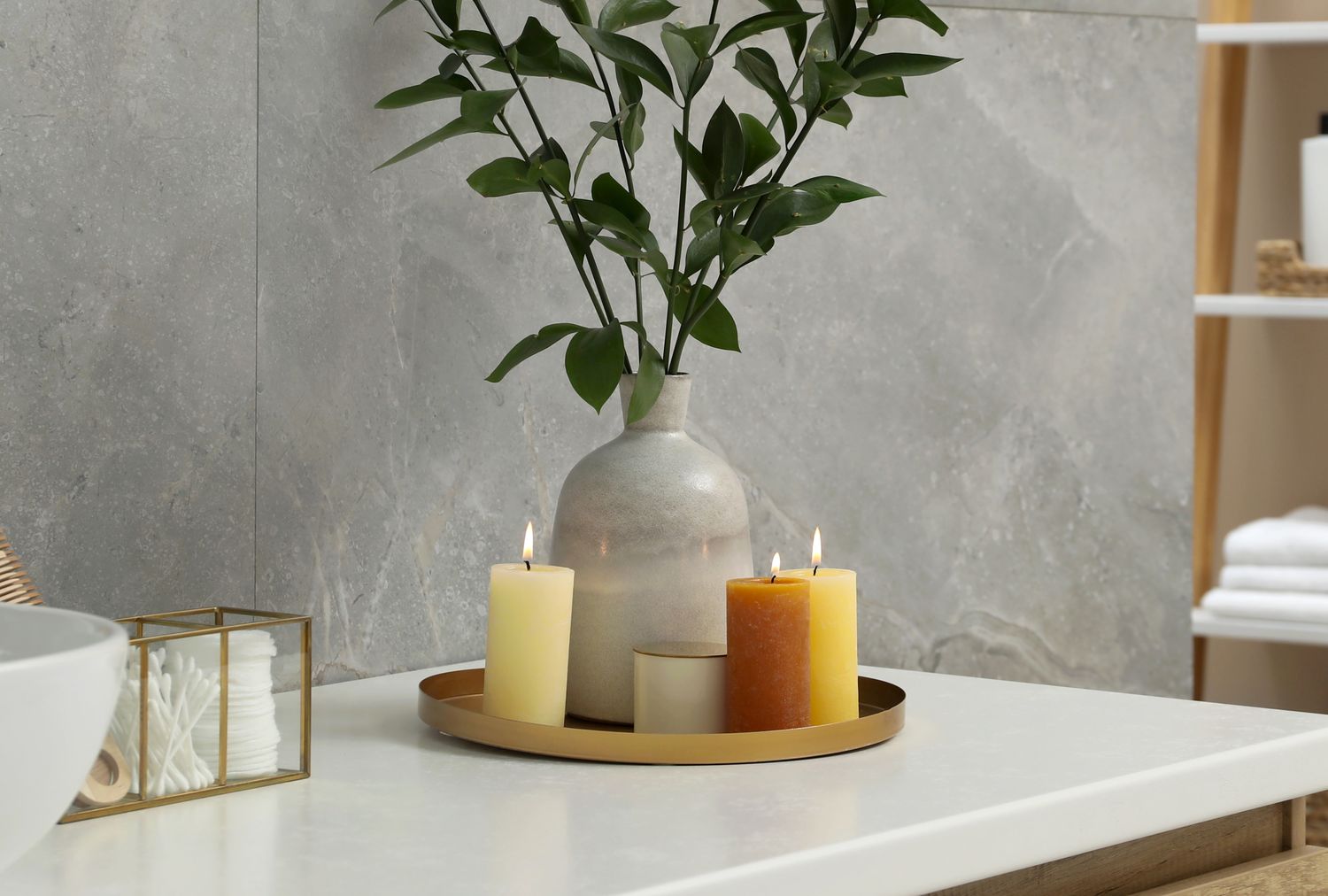 Candles on a decorative tray next to a vase with branches