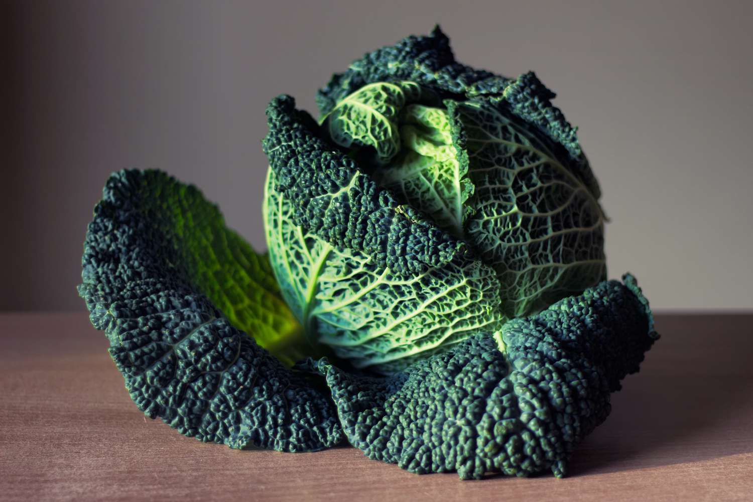 whole savoy cabbage on a wooden surface