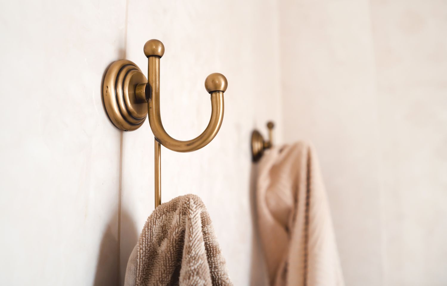 Towels hang on vintage stylish bathroom hooks in light shades.