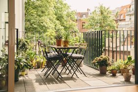 Outdoor balcony with a table chairs and plants overlooking a residential area