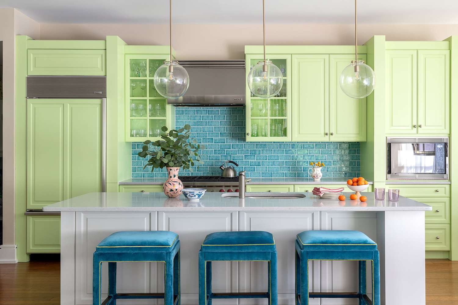 Kitchen with pastel green cabinets and a blue tile backsplash