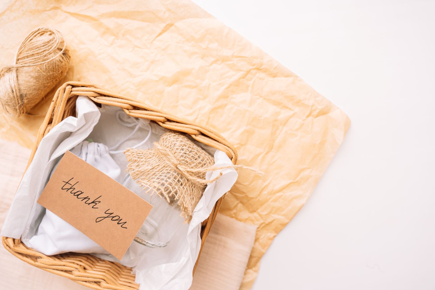 A thankyou card on top of a gift basket with wrapped items