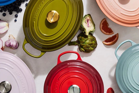 Top view of various Le Creuset Dutch ovens and vegetables arranged on a surface