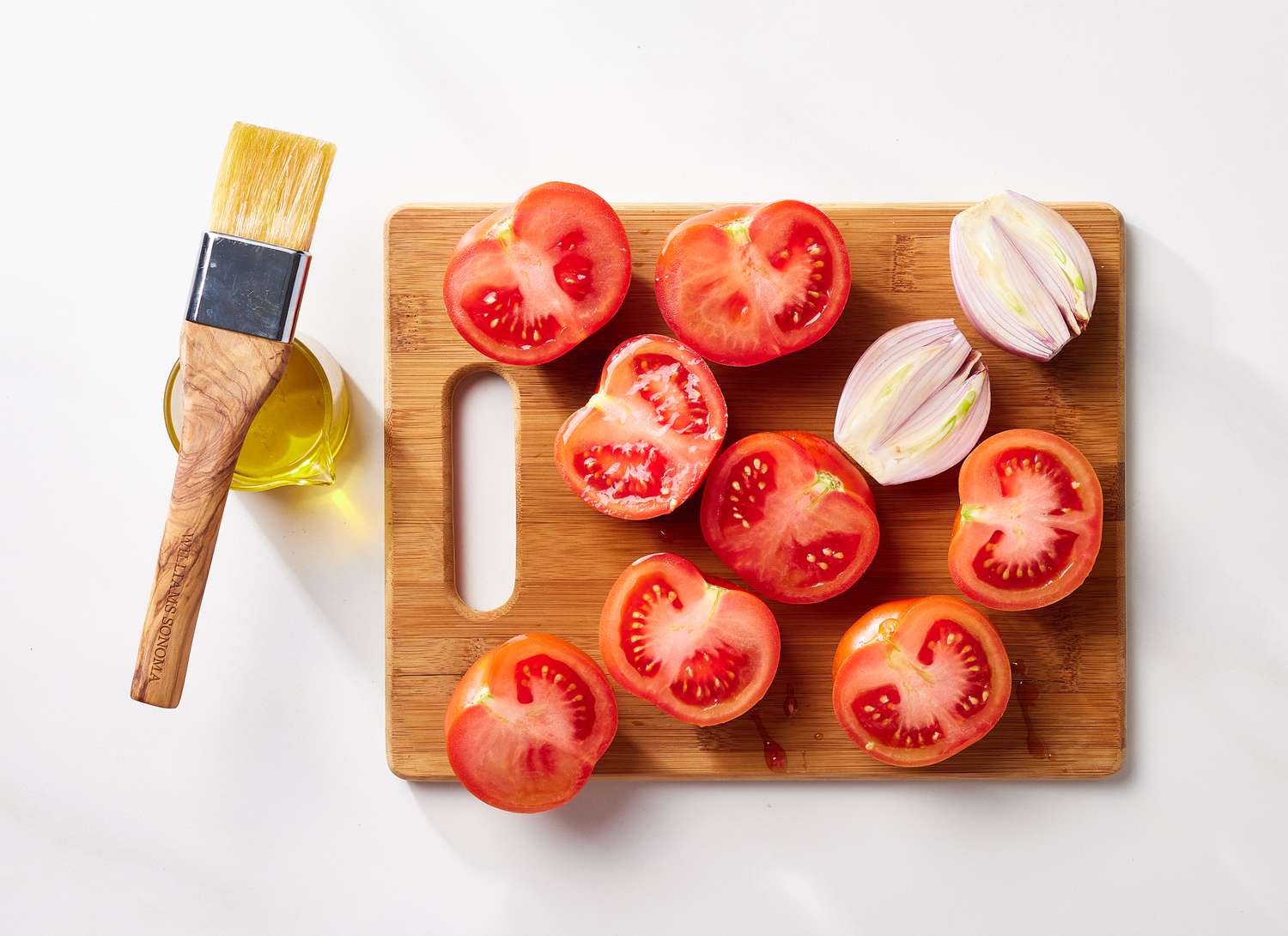overhead view of tomatoes on cutting board with olive oil 