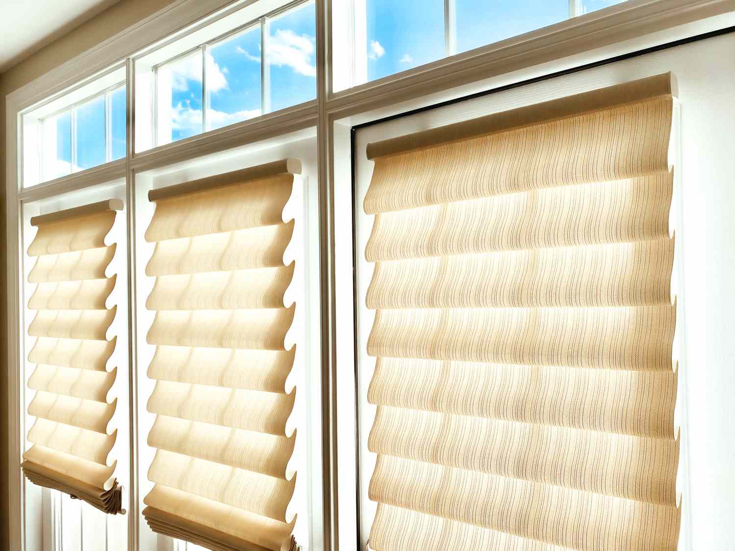 Three large windows with beige blinds covering them