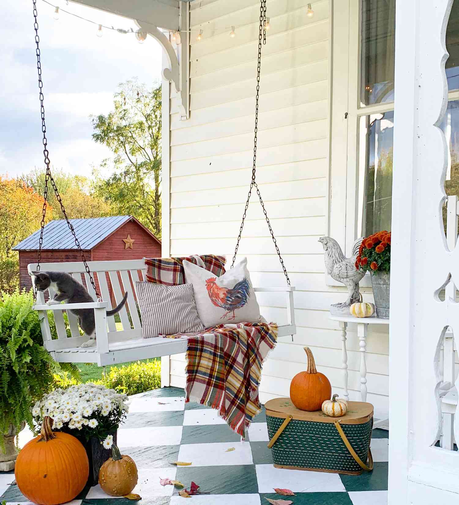 fall porch swing with plaid throw flowers and pumpkins