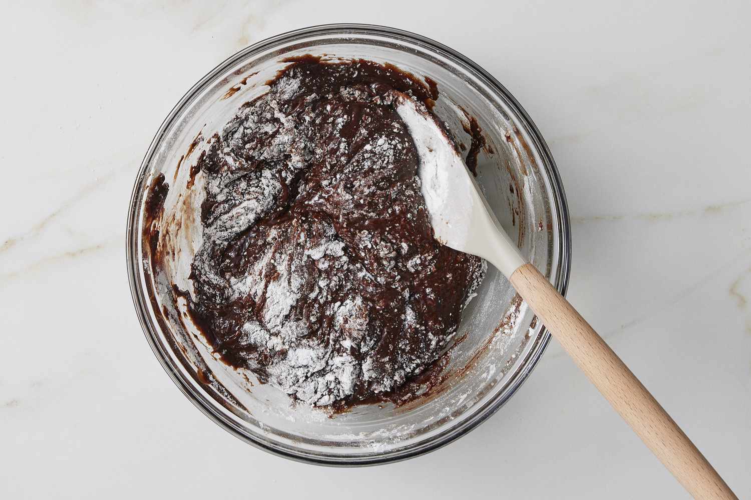 Flour and melted chocolate in bowl with whisk