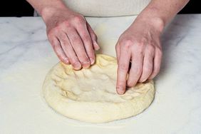 person kneading pizza dough