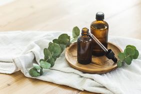 Two amber glass bottles with a dropper on a wooden plate eucalyptus leaves and cloth around them