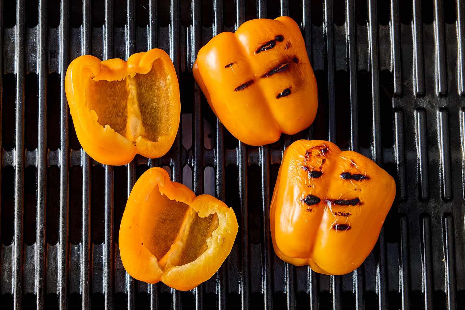 Grilled yellow bell pepper halves on a grill