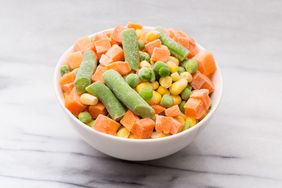 A bowl of mixed frozen vegetables including carrots green beans peas and corn