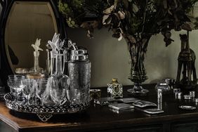 An arrangement of glassware, a mirror, and a bouquet of flowers on a table