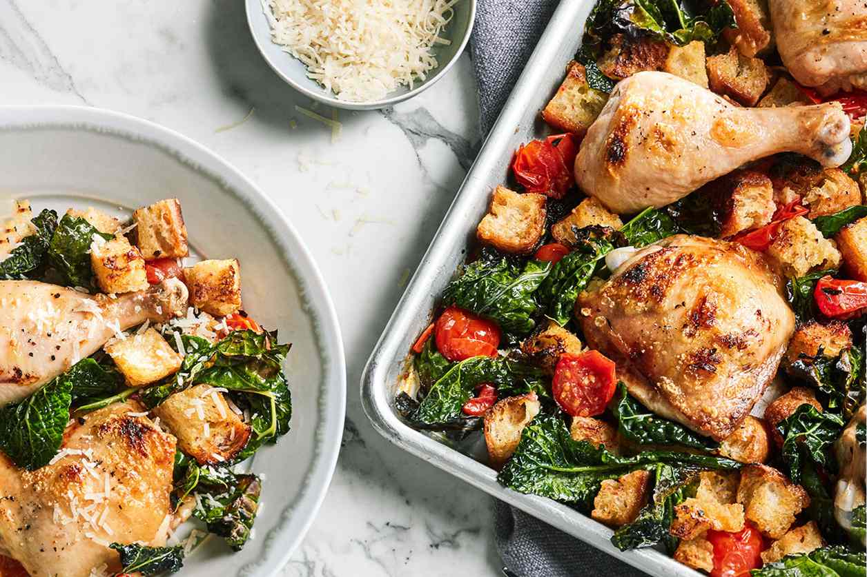 plate and sheet of chicken and kale dinner on marble table top