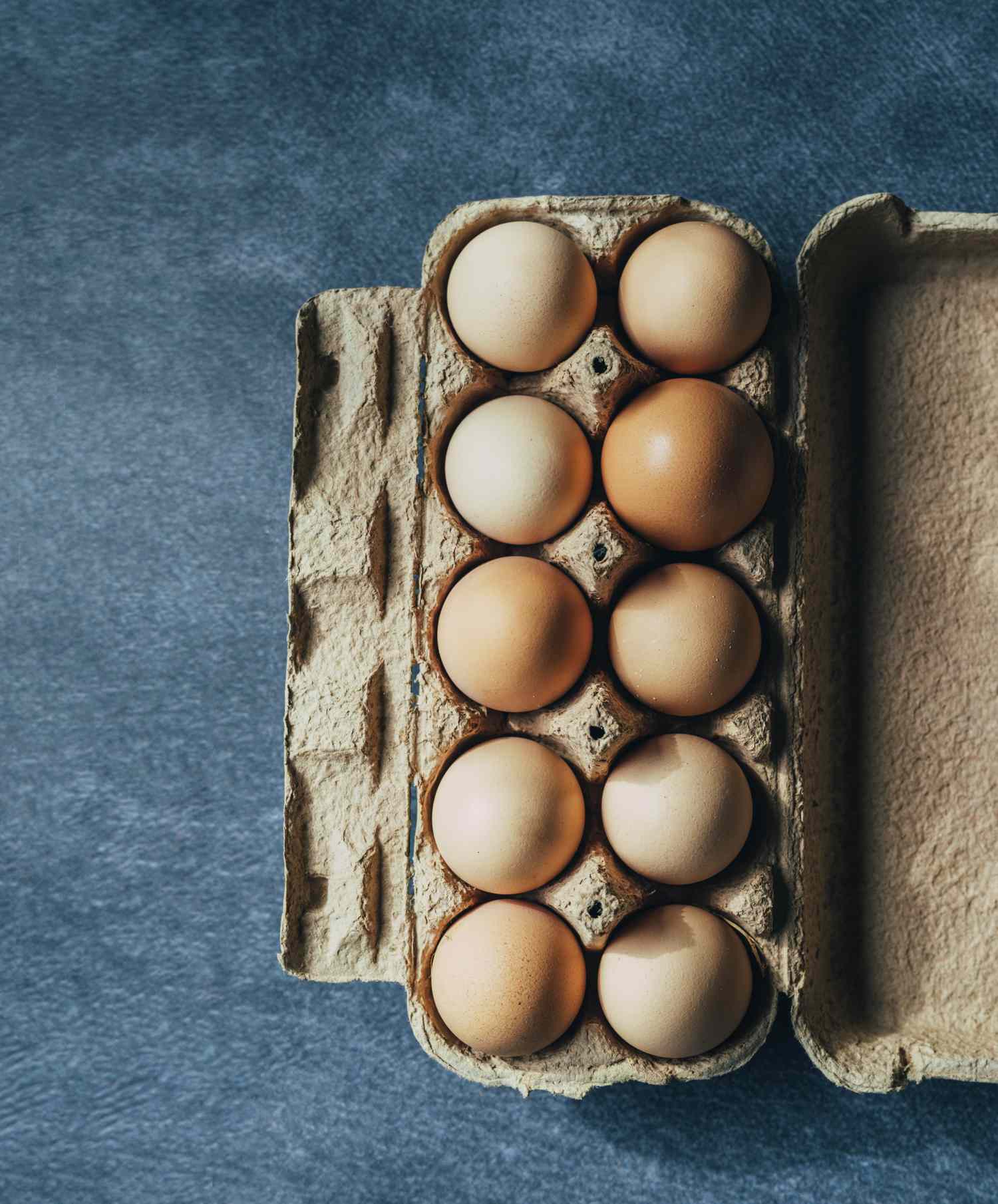 An open carton containing eight brown eggs neatly arranged