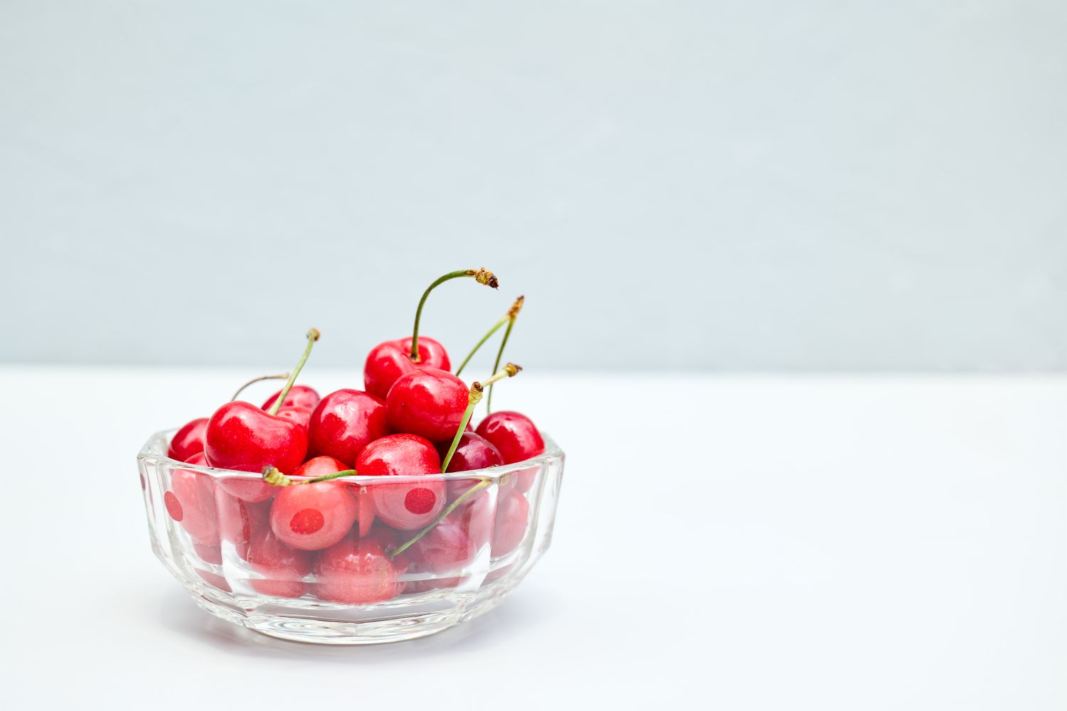 montmorency sour cherries in glass bowl on light surface