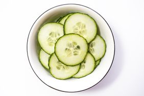 Sliced cucumbers in a white bowl. 