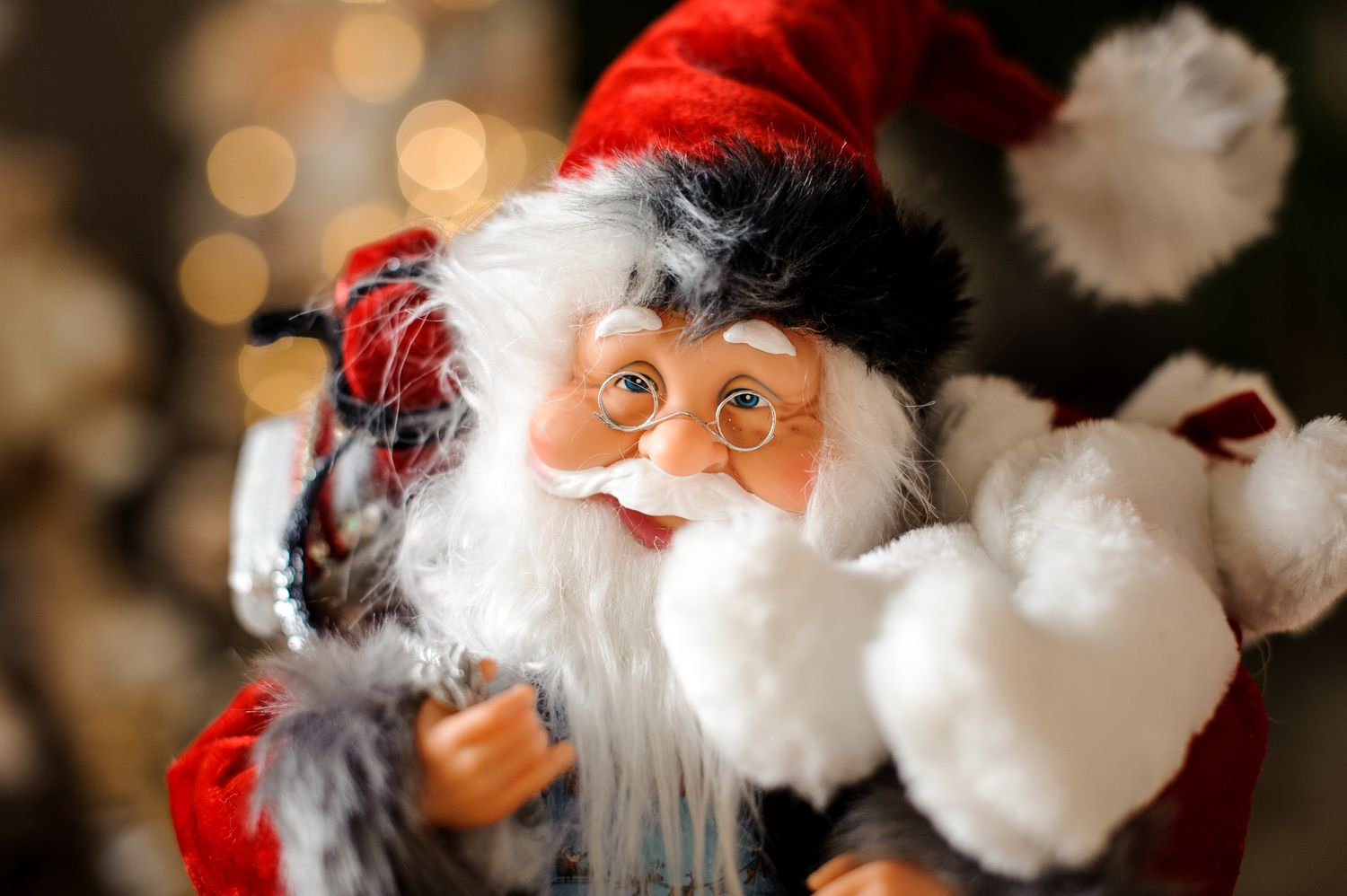 Portrait of toy santa claus with glasses with white beard in bright red suit and hat.