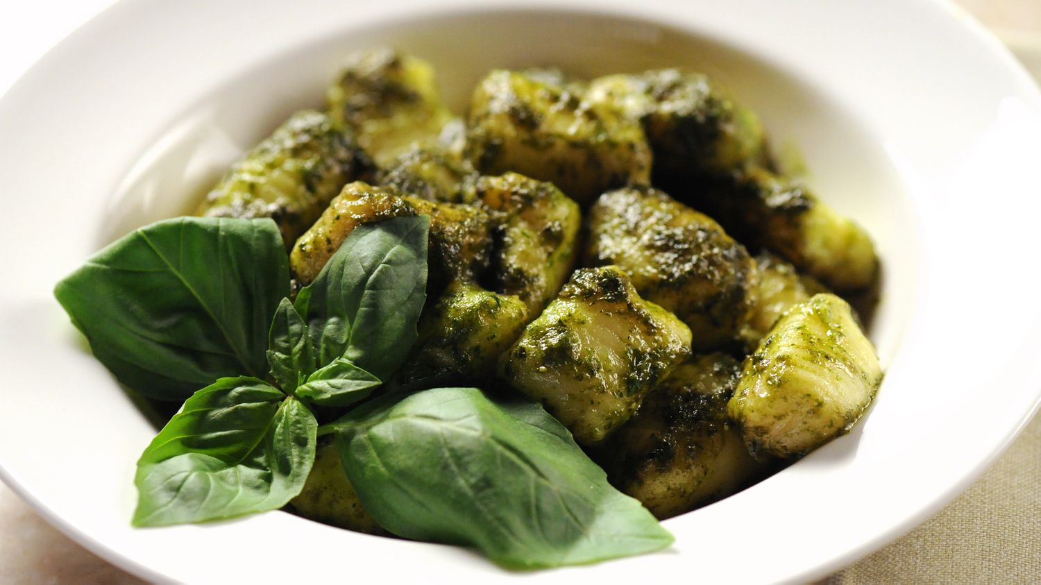 potato gnocchi with basil pesto in white bowl