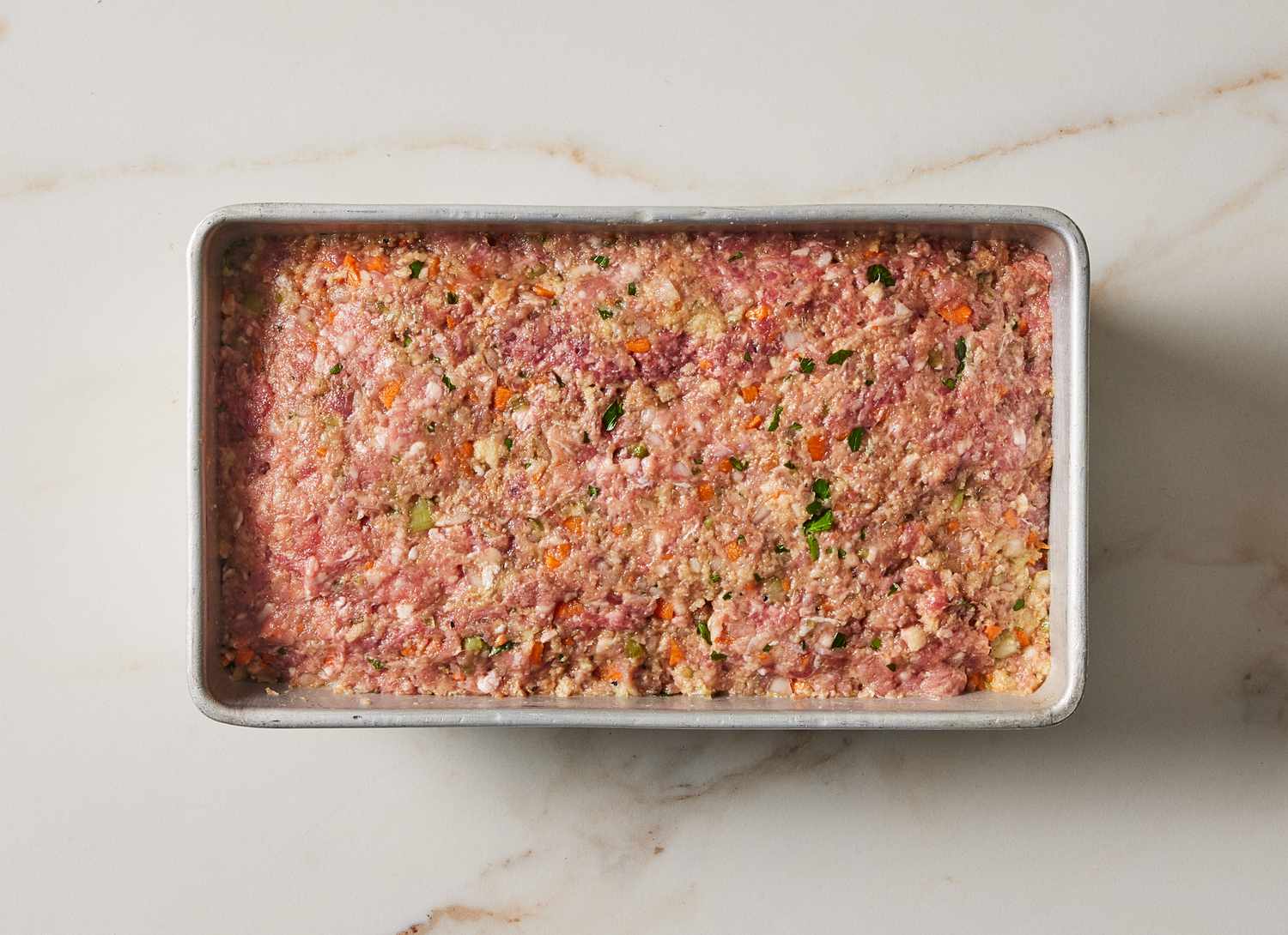 raw meatloaf ingredients mixed together in a loaf pan