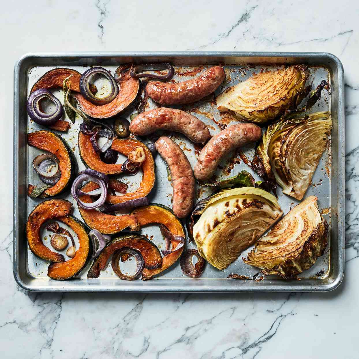 sausages cabbage vegetables on baking sheet