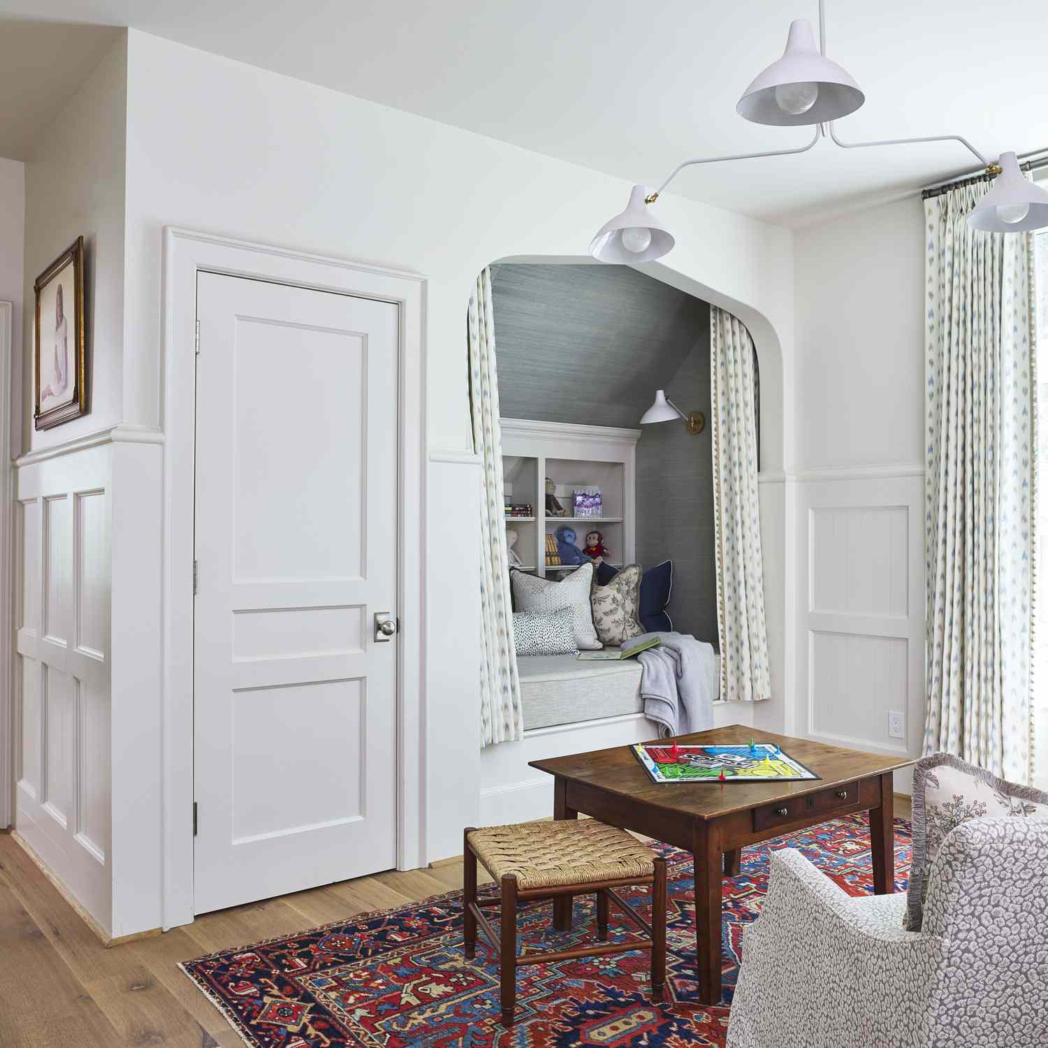 A cozy room with a small table, chairs, an alcove bed, and a patterned rug