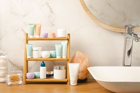Bathroom counter with neatly arranged skincare products on a wooden rack next to a salt lamp and a sink