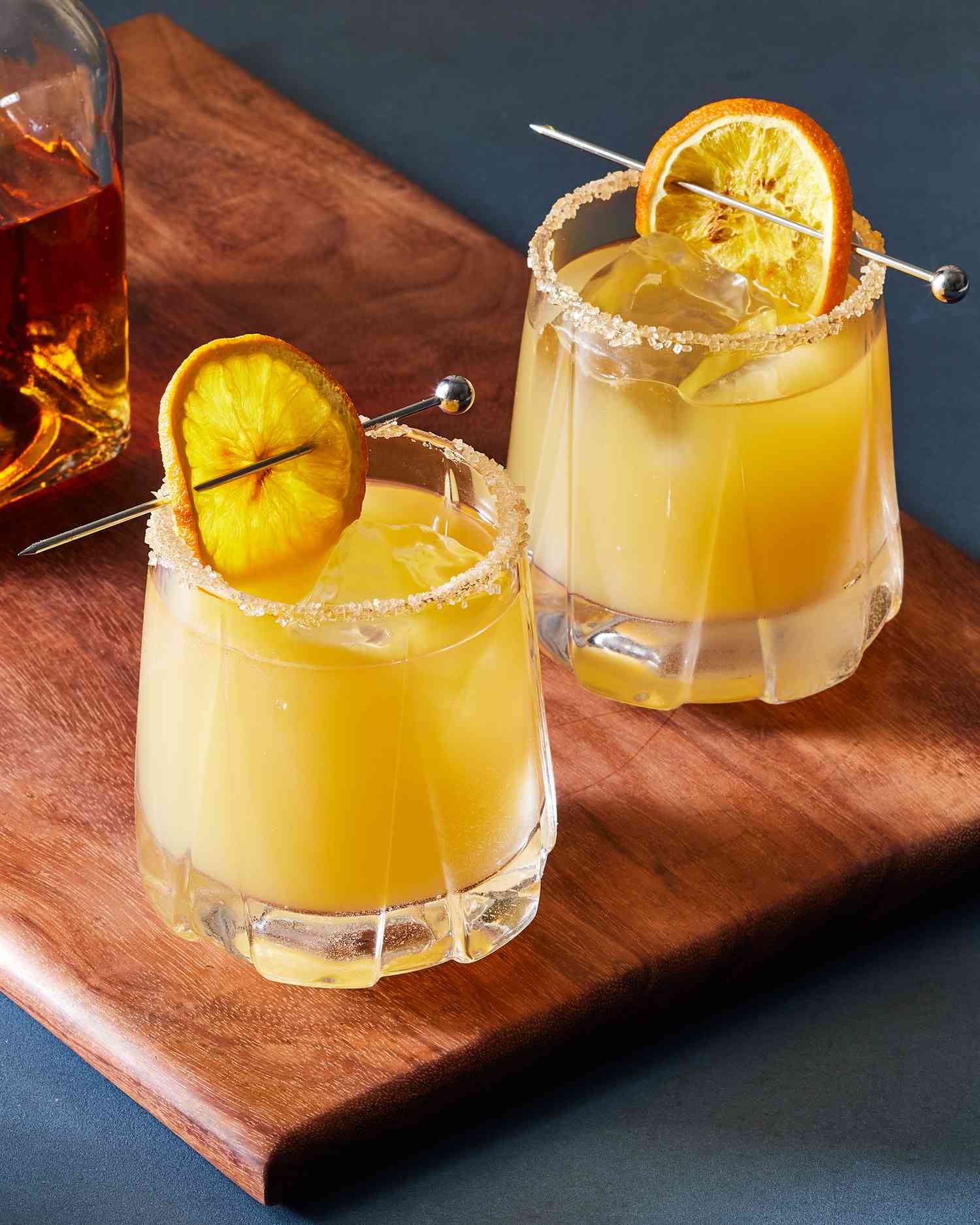vertical format of two whiskey sour cocktails on a cutting board