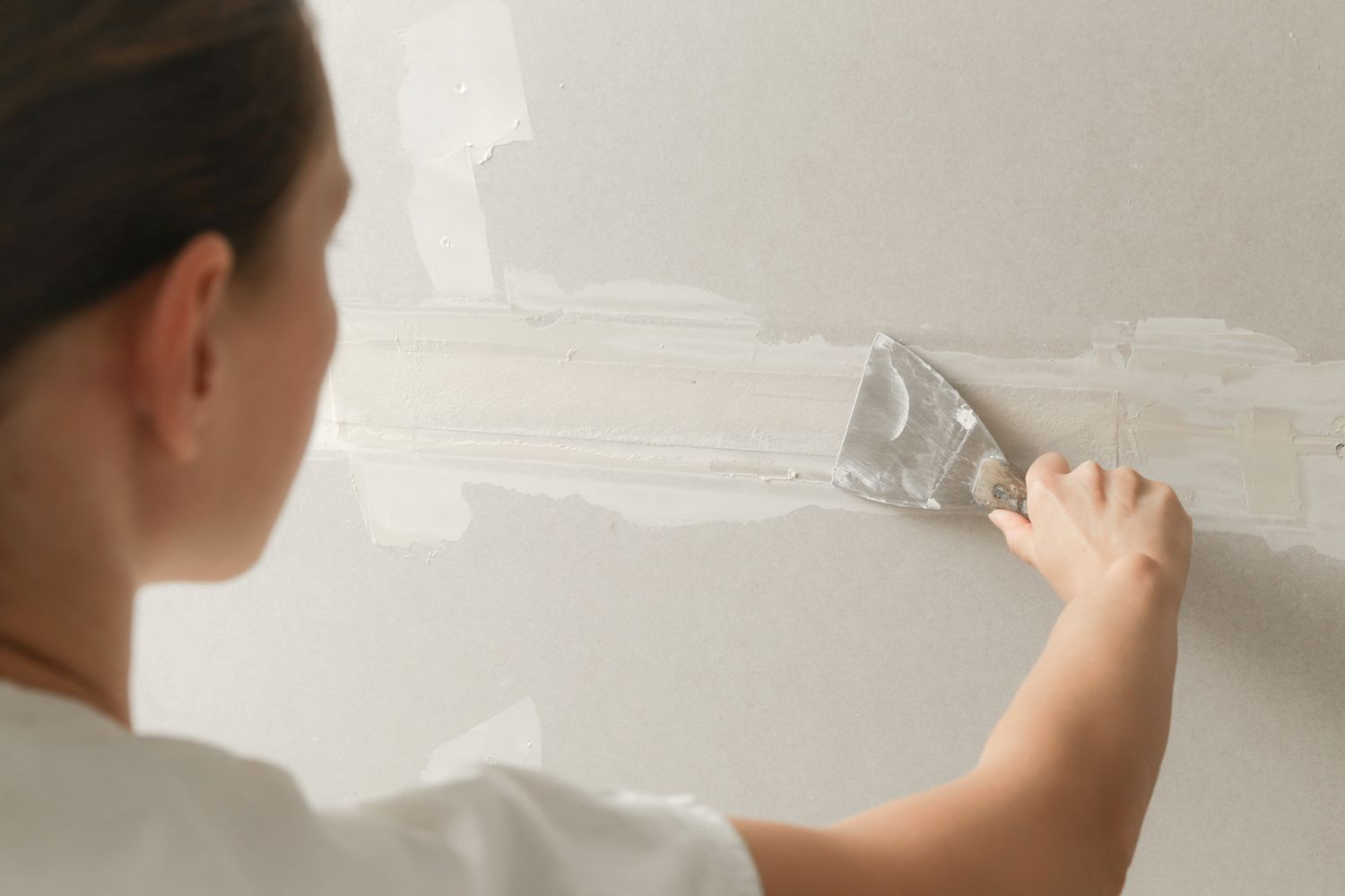 Person applying wallpaper or joint compound using a flat trowel