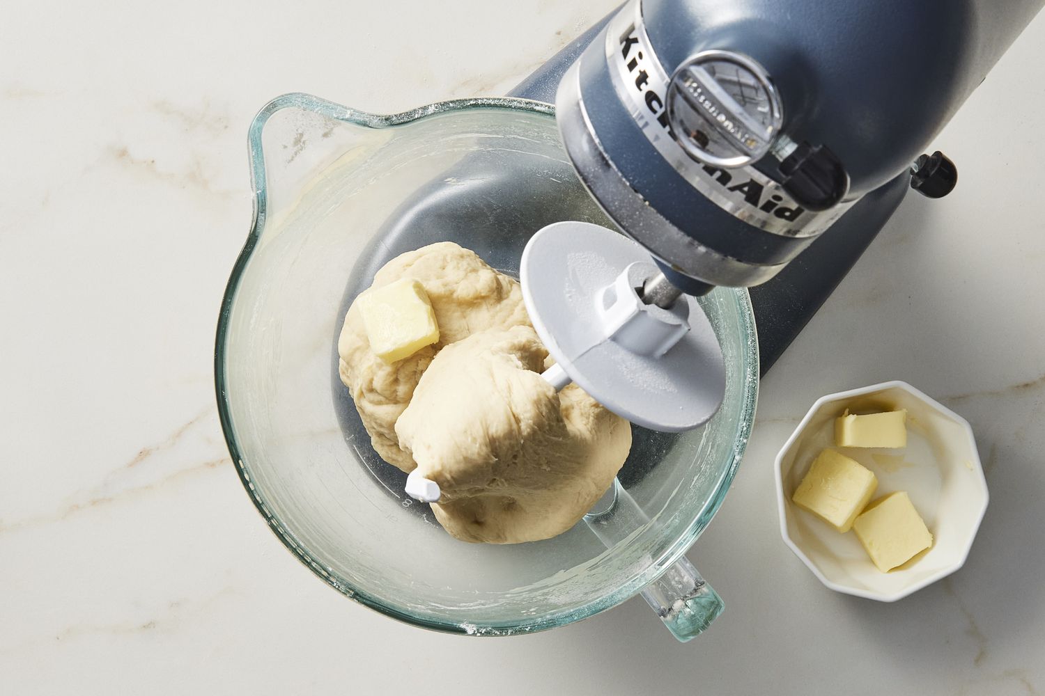 Dough and butter in glass bowl under stand mixer 