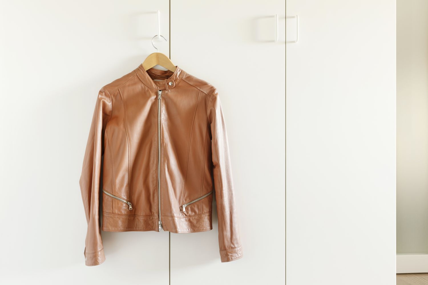 A leather jacket hanging on a white wardrobe door