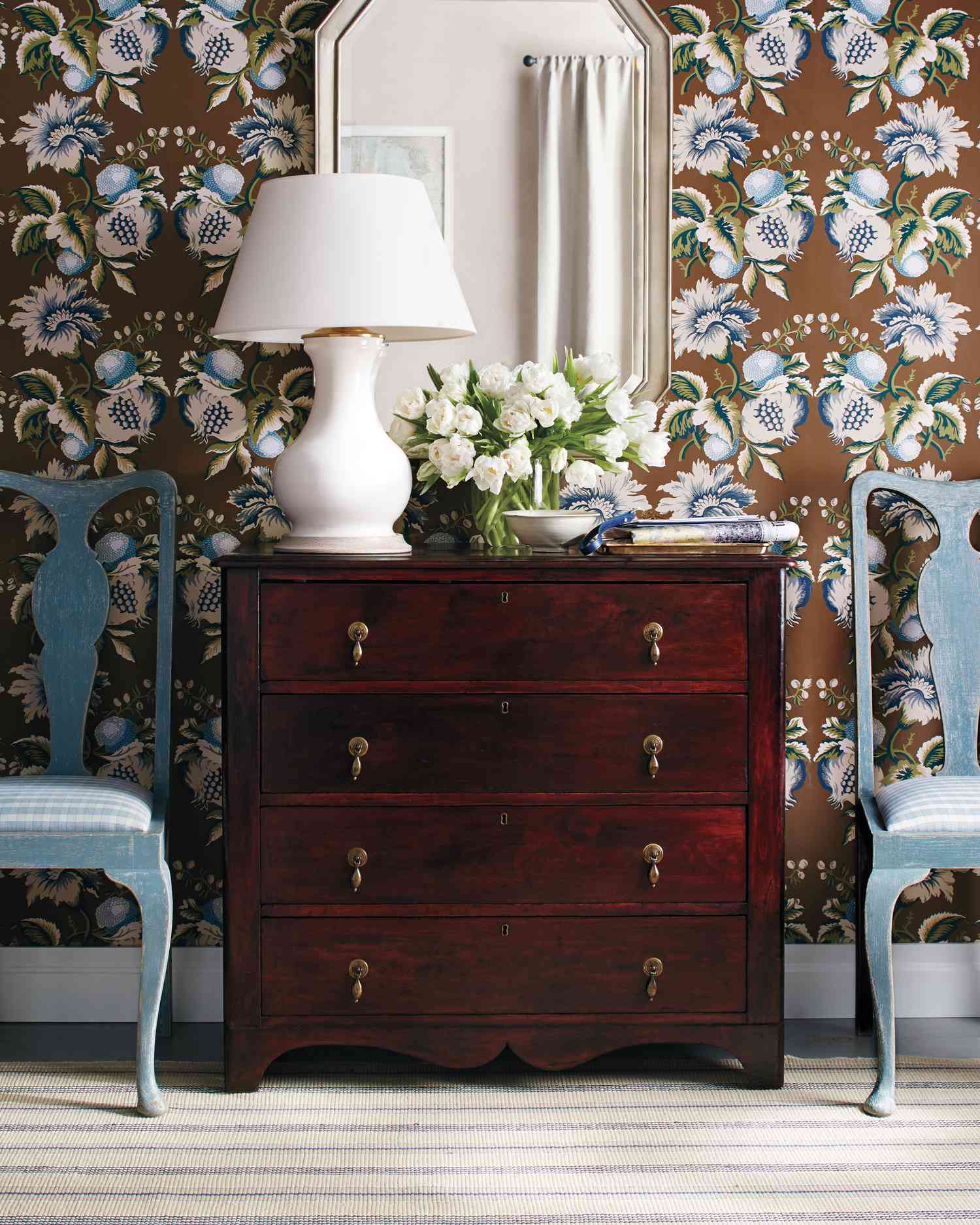Wooden dresser with floral wallpaper and white lamp