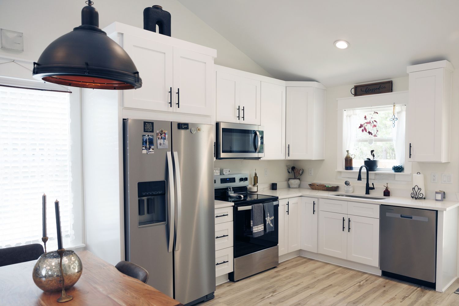 Modern kitchen with white cabinets stainless steel appliances and a wooden dining table